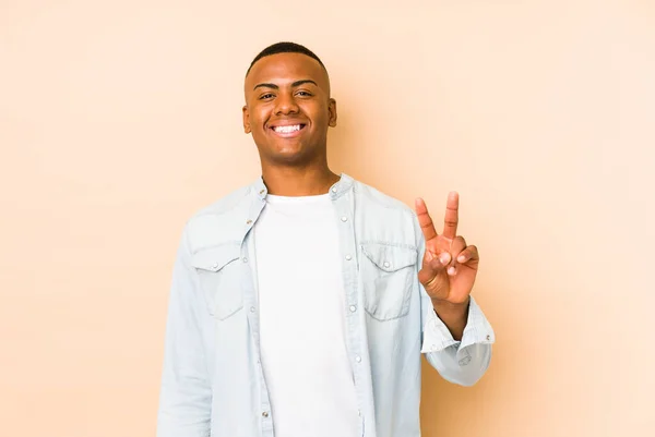 Joven Latino Aislado Sobre Fondo Beige Mostrando Signo Victoria Sonriendo — Foto de Stock