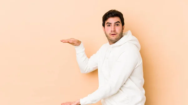 Young Man Isolated Beige Background Shocked Amazed Holding Copy Space — Stock Photo, Image