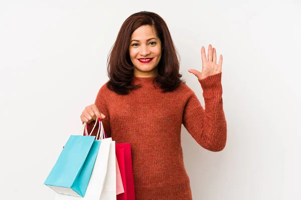 Medelålders Latinamerikansk Kvinna Håller Shoppingpåse Isolerad Ler Glad Visar Nummer — Stockfoto