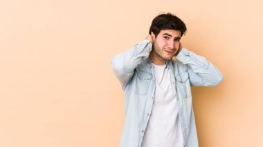 Bej arka planda izole edilmiş genç bir adam kafasının arkasına dokunuyor, düşünüyor ve bir seçim yapıyor..