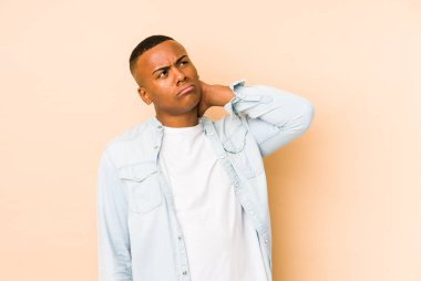 Genç Latin bir adam bej arka planda izole edilmiş, sabit yaşam tarzından dolayı boyun ağrısı çekiyor..