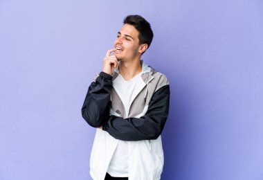 Mor arka planda izole edilmiş genç beyaz adam rahatlamış bir şeyin fotokopi odasına baktığını düşünüyor..