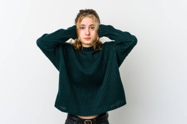 Beyaz arka plandaki genç beyaz kadın kulaklarını elleriyle kapatıyor ve çok fazla ses duymamaya çalışıyor..