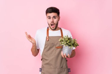 Kafkasyalı genç bahçıvan elinde bir bitki tutuyor. Şaşırmış ve şok olmuş..