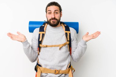Genç bir sırt çantalı adam beyaz bir arka planda izole edilmiş. Kafası karışmış ve omuz silkiyor. Kopya alanını tutmak için..