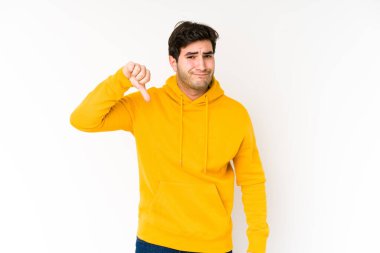 Beyaz arka planda izole edilmiş genç adam baş parmağını aşağı gösteriyor, hayal kırıklığı konsepti..