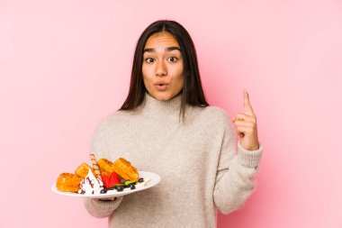 Elinde waffle tutan Asyalı genç bir kadın harika bir fikre sahip, yaratıcılık kavramı..