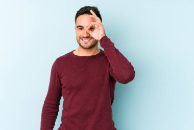 Kafkasyalı genç adam mavi arka planda izole edildi. Heyecanlı görünüyor..