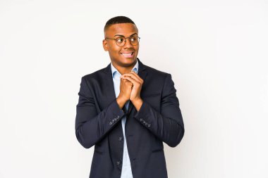 Beyaz arka planda izole edilmiş genç iş adamı ellerini çenesinin altında tutuyor, mutlu bir şekilde yan tarafa bakıyor..