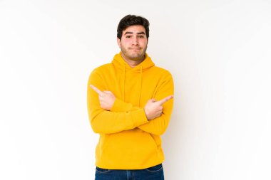 Beyaz arka plan noktalarından izole edilmiş genç adam iki seçenek arasında seçim yapmaya çalışıyor..