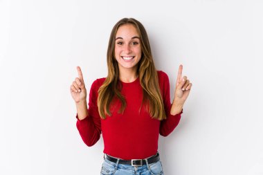 Kafkasyalı genç bir kadın yalnız poz veriyor. İki ön parmağı da boş bir alan gösteriyor..