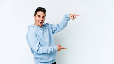 Beyaz arka planda izole edilmiş genç beyaz bir adam işaret parmağıyla fotokopi alanını işaret ederek heyecan ve arzusunu ifade ediyor..