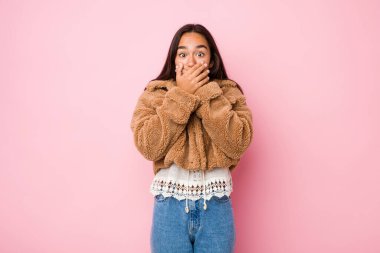 Koyun derisi ceket giyen genç Hintli kadın elleriyle ağzını kapatıyor..