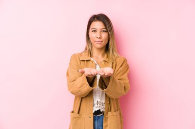 Kafkasyalı genç bir kadın avuçlarıyla bir şey tutarak kameraya poz veriyor..