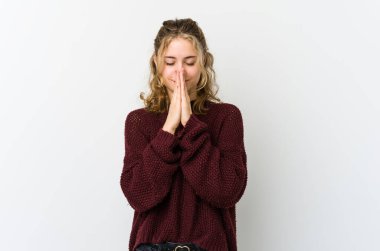 Beyaz arka planda el ele tutuşan beyaz tenli genç bir kadın ağzının kenarında dua ediyor, kendinden emin..