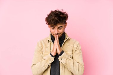 Arka planda yalnız poz veren genç bir Arap, el ele tutuşup, ağzının kenarında dua ediyor, kendinden emin hissediyor..