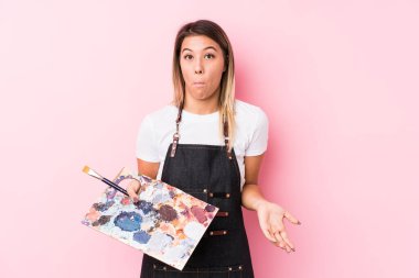 Kafkasyalı genç bir kadın soyutlanmış bir palet tutuyor omuzlarını silkiyor ve gözleri açık..