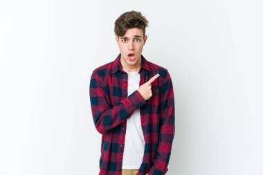 Beyaz arka planda izole edilmiş genç beyaz adam yan tarafı işaret ediyor