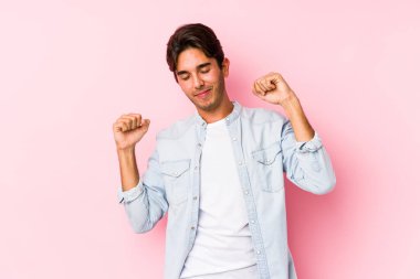 Pembe arka planda poz veren beyaz bir genç, izole edilmiş kollar, rahat bir pozisyon..