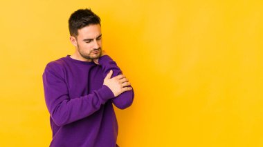 Kafkasyalı genç adam sarı fırında izole edilmiş, dirsek masajı yapıyor, kötü bir hareketin ardından acı çekiyor..