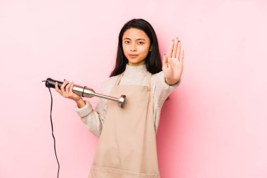 Karıştırıcıyı tutan genç Çinli kadının kafası karışmış ve kendinden emin değil..