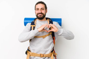 Sırt çantalı genç adam beyaz bir arka planda izole edilmiş gülümsüyor ve elleriyle kalp şeklini gösteriyor..