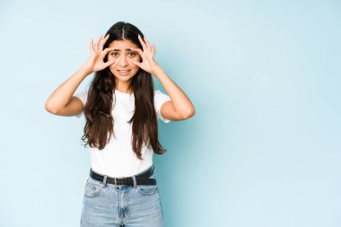 Mavi arka plandaki genç Hintli kadın bir başarı fırsatı bulmak için gözlerini açık tutuyor..