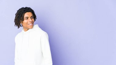 Genç Afrikalı Amerikalı Rasta adam gülümseyen, neşeli ve keyifli bir şekilde yana bakıyor..