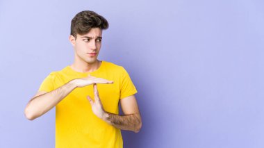 Mor arka planda izole edilmiş genç beyaz bir adam bir mola hareketi gösteriyor..