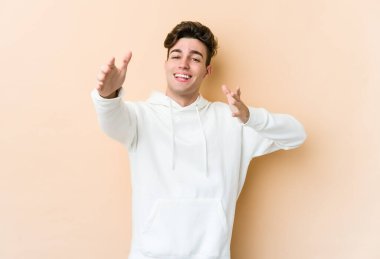 Beyazlı genç adam bej arka planda izole edilmiş kameraya sarıldığı için kendinden emin hissediyor..