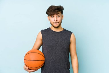 Genç Arap adam yalnız başına basket oynuyor. Kafası karışmış, kendinden emin değil..