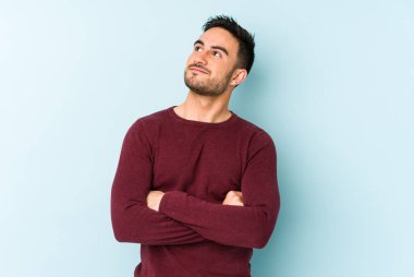 Kafkasyalı genç adam mavi arka planda izole edilmiş hedeflerine ve amaçlarına ulaşma hayali kuruyor.