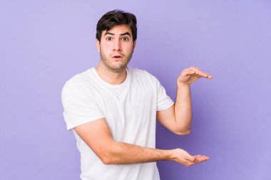 Mor arka planda izole edilmiş genç adam elleri arasında bir kopya alanı tutarken şok olmuş ve hayrete düşmüştü..