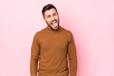 Pembe arka planda genç beyaz bir adam izole edilmiş komik ve dost canlısı bir dil kullanıyor..