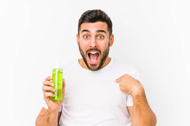 Kafkasyalı genç bir adam elinde aloe vera ile nemlendirici tutarken kendini göstererek şaşırdı ve gülümsedi..