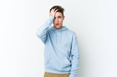 Beyaz arka planda izole edilmiş genç beyaz bir adam bir şeyi unutuyor. Alnına avuç içi ve gözlerini kapayarak vuruyor..