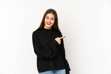 Beyaz arka planda izole edilmiş genç beyaz bir kadın gülümsüyor ve boş alanda bir şeyler gösteriyor..