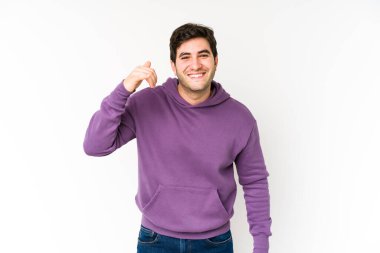 Beyaz arka planda izole edilmiş genç bir adam bir şeye gülüyor, elleriyle ağzını kapatıyor..