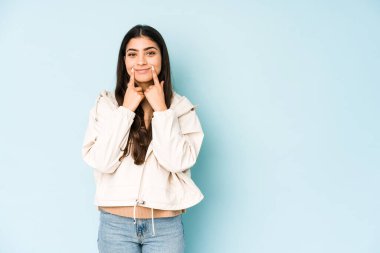 Mavi arka planda genç Hintli kadın iki seçenek arasında şüphe ediyor.