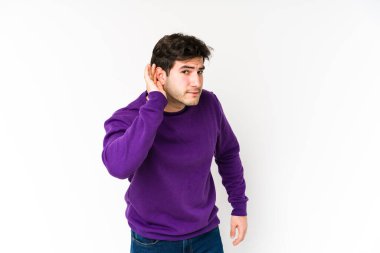 Beyaz arka planda yaşayan genç bir adam bir dedikoduyu dinlemeye çalışıyor..