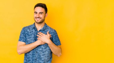 Sarı fırında izole edilmiş beyaz bir genç, dost bir ifadeye sahip, avuçlarını göğsüne bastırıyor. Aşk konsepti.