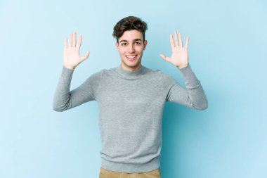 Mavi arka planda izole edilmiş genç beyaz adam hoş bir sürpriz alıyor, heyecanlı ve el kaldırıyor..