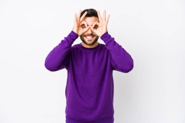 Beyaz arka planda beyaz tenli genç bir adam izole edilmiş, gözlerinde sorun yok işareti var.