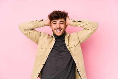 Arka planda poz veren genç bir Arap adam neşeli bir şekilde el ele tutuşarak gülüyor. Mutluluk kavramı.