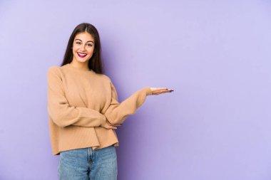 Mor arka planda izole edilmiş genç beyaz kadın bir avuç içinde fotokopi alanı ve belinde bir el daha gösteriyor..