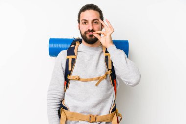 Sırt çantalı genç adam beyaz bir arka planda izole edilmiş ve parmakları dudaklarında bir sır saklıyor..