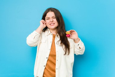 Genç kavisli kadın elleriyle kulaklarını kapatan kurabiyeler tutuyor..