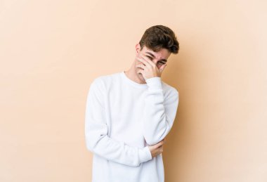 Beyaz tenli genç adam bej arka planda izole edilmiş gülerek, kaygısız, doğal duygularla gülüyor..