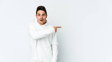 Beyaz arka planda izole edilmiş genç beyaz adam yan tarafı işaret ediyor