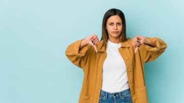 Mavi arka planda izole edilmiş genç bir kadın hoşlanmadığı bir hareket gösteriyor. Anlaşmazlık konsepti.